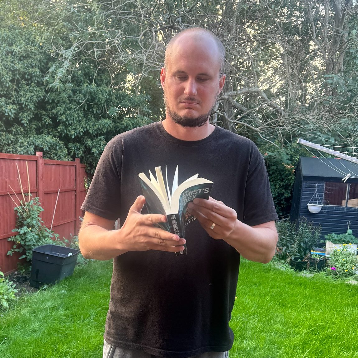 Luke Richardson flicking through a paperback copy of The Alchemist’s Codex