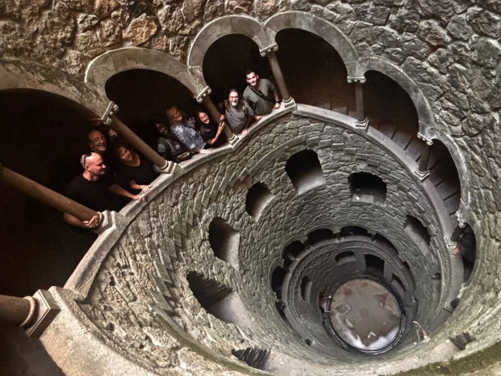 Readers smiling from the spiral staircase of the Initiation Well at Quinta da Regaleira, Sintra