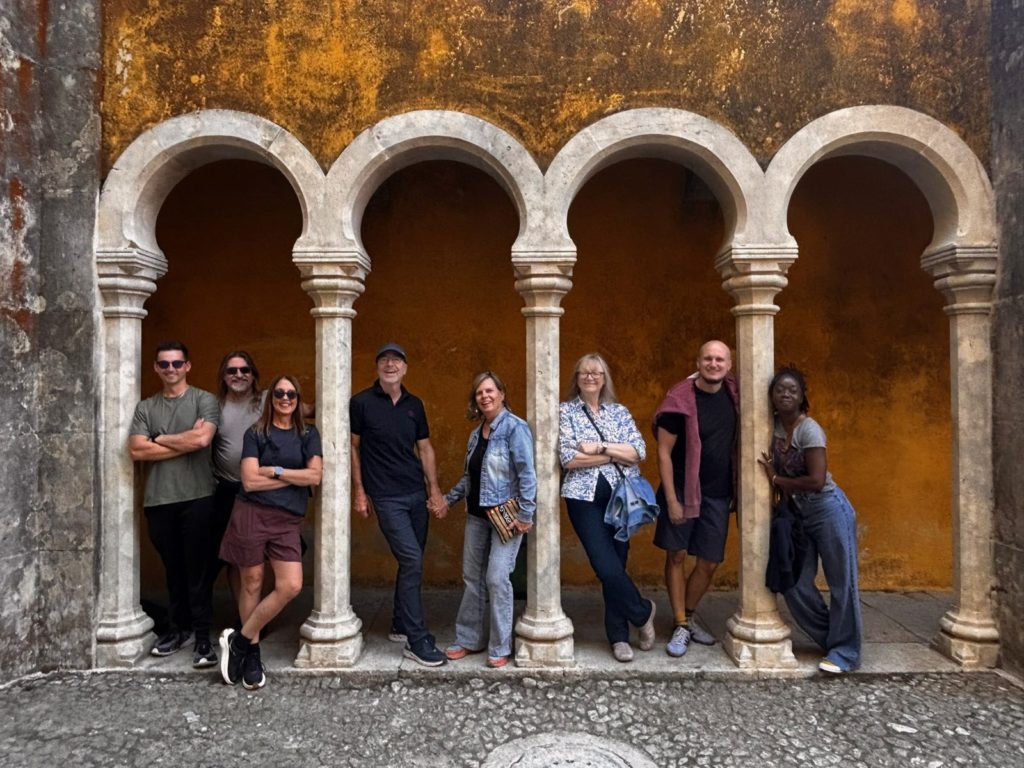 Adventure Society Expedition group posing beneath stone arches against an ochre wall at Pena Palace, Sintra